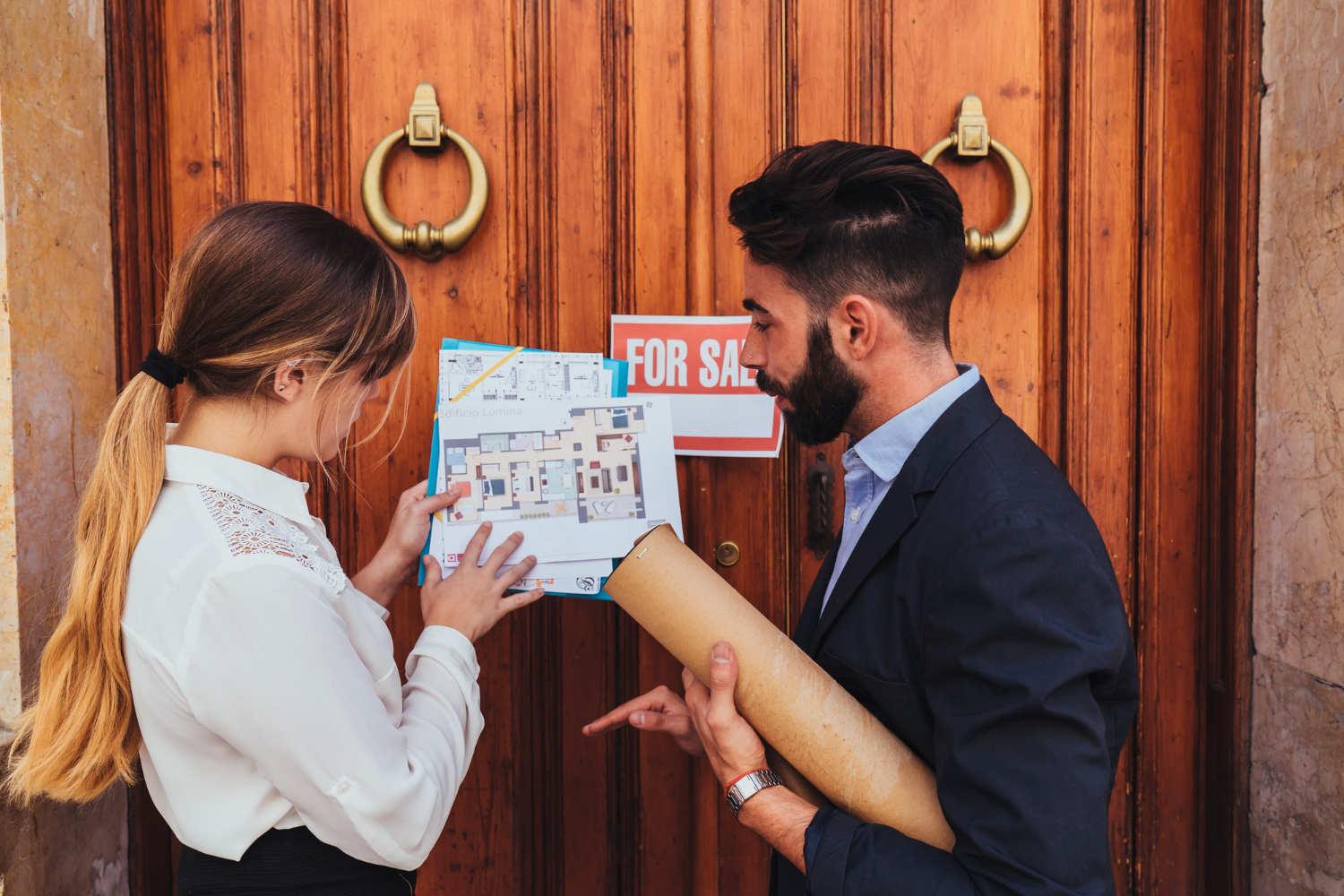 Two people discussing the house plan before entering a house for sale.